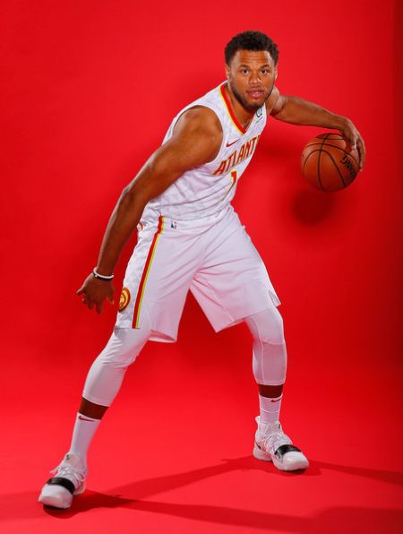Justin Anderson holding a basketball for a photoshoot with red background.